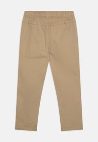 Tan trousers with an elastic waistband, straight legs, smooth fabric, and simple stitching. No pockets or embellishments are visible.