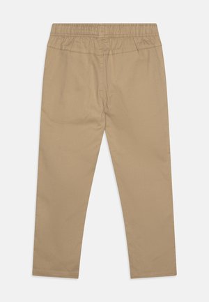 Beżowe spodnie z prostymi nogawkami i elastycznym pasem, z tylnym szwem, wyłożone płasko na białym tle.