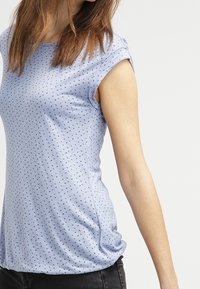 Ljusblå kortärmad skjorta i mjukt material, med ett litet triangulärt mönster. Rundad halsringning och avslappnad passform.