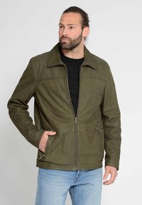 Olivgrüne Lederjacke mit Reißverschluss, spitzem Kragen und zwei Seitentaschen. Texturierte Oberfläche und kontrastierende Nähte an den Schultern.