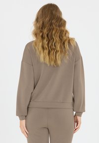 Langsleeve, oversized bruine sweatshirt met ribgebreide manchetten en zoom. Glad textuur, ontspannen pasvorm en minimalistisch ontwerp.