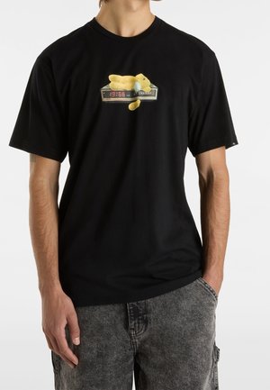 T-shirt en coton noir avec un graphisme d'un ours en peluche jaune allongé sur un réveil affichant 19:66. Manches courtes, coupe décontractée.