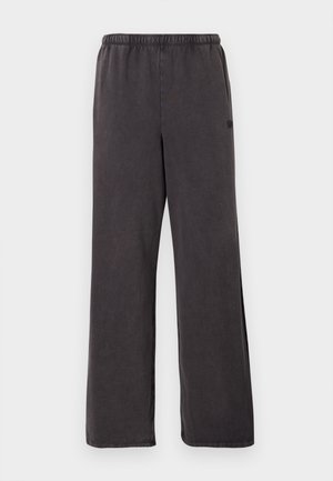 Pantalon de survêtement gris foncé à coupe ample avec taille élastique, jambes droites et poches latérales discrètes visibles sur fond blanc.