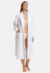 Vit frottébadrock med sjalkrage, långa ärmar och två framfickor, med en mjuk textur och knälång design.