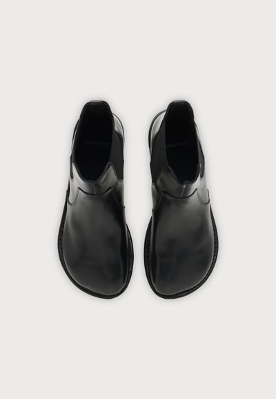 Chaussures en cuir noir à enfiler avec bouts arrondis et panneaux latéraux élastiques, vues de dessus sur fond blanc uni.