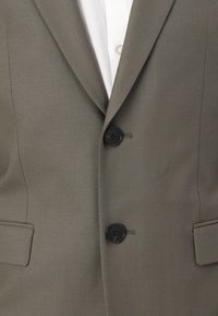 Tailored dark olive green blazer with two black buttons, notched lapels, and two front pockets. Smooth fabric with minimal texture.