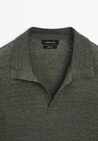 Donkergroene linnen polo met een gestructureerde oppervlakte, voorzien van een v-hals kraag en een label met de tekst "Massimo Dutti."
