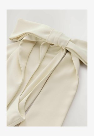 Ivory fabric bow with a soft, textured finish, featuring draped elements and trailing ends, secured at the center with a smooth tie.