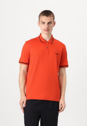 Rød polo-skjorte med svart kant på krage og ermer, logo på brystet, knappestolpe og et glatt, lett stoff.