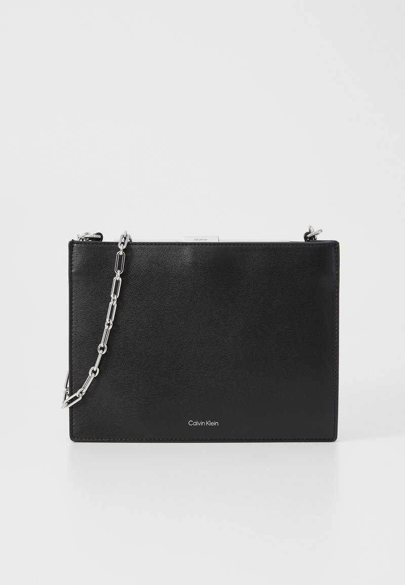 Calvin Klein black handbag made of textured leather, featuring a chain strap and a smooth metal clasp. Simple rectangular design with logo detail.