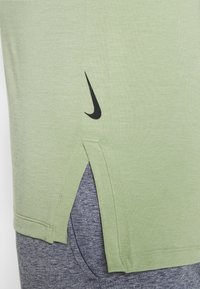 Ljust grön Nike T-shirt med svart logotyp, korta sidslutningar och en mjuk, slät textur. Sytt fåll och avslappnad passform.