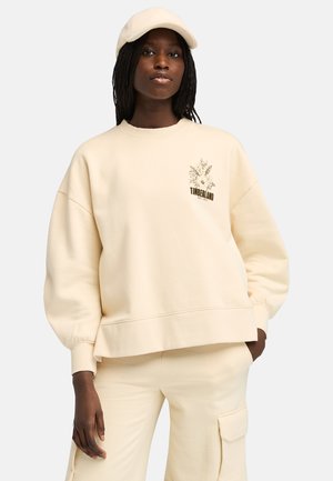 Felpa crema con vestibilità rilassata, polsini a costine e un piccolo motivo floreale. Abbinata a pantaloni cargo crema coordinati.