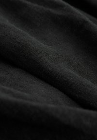 Čierna látka s jemnou textúrou, s jemným tkaním. Materiál vyzerá mierne pokrčený s hlbokým matným povrchom.