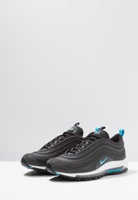 Schwarze Nike Air Max 97 Schuhe zeichnen sich durch ein welliges Design, Mesh- und synthetische Materialien, blaue Akzente und eine sichtbare Air-Dämpfung in der Sohle aus.