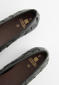 Melnas austas sporta kurpes ar gludu tekstūru, noapaļotu purngala daļu un mīkstu iekšējo zolīti. Zīmola nosaukums "Forever Comfort" iegravēts zeltā iekšpusē. Izmērs 40.