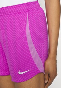 Pantalones cortos deportivos rosa con un patrón geométrico texturizado, que presentan un panel lateral de malla, una cintura elástica y un pequeño acento de logo blanco.