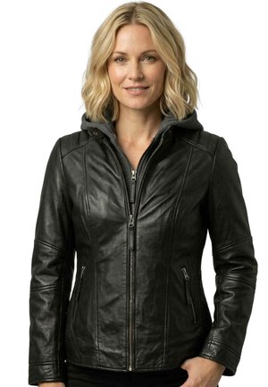 Frau mit blondem Haar, die eine schwarze Lederjacke mit Reißverschluss vorne und seitlichen Reißverschlusstaschen über einem grauen Kapuzenpullover trägt.