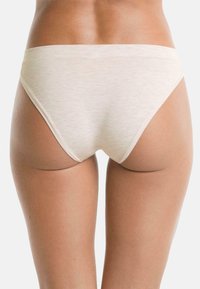 Korte damesondergoed in een lichtbeige stof met een gladde textuur en een low-rise ontwerp, met minimale stiksels en geen zichtbare naden.