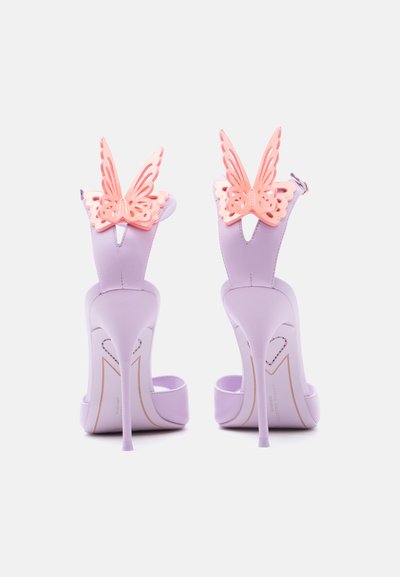 Λιλά σανδάλια με ψηλά τακούνια στιλέτο και ροζ διακοσμητικά πεταλούδας στα λουριά του αστραγάλου, εμφανιζόμενα από πίσω.