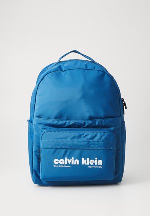 Blue backpack made of nylon, featuring a rounded top, front zip pocket, and white logo text. Smooth texture with reinforced handles.