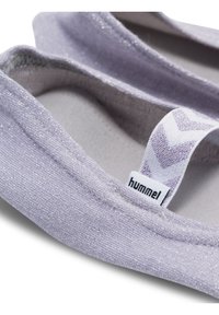 Närbild på ljuslila glittriga balettskor med ett vitt elastiskt band som har lila zigzag-mönster och en "hummel"-logga.