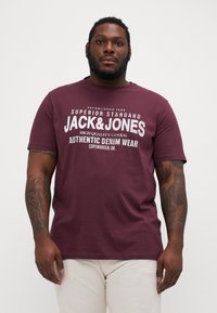 Bordová bavlněná tričko s kulatým výstřihem, s bílým potiskem: "JACK & JONES AUTHENTIC DENIM WEAR" a detaily z roku 1990.