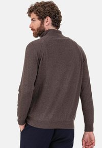 Pull en maille marron avec un col montant, des manches longues et un ourlet côtelé. Texture douce et coupe ajustée, mettant en valeur une finition lisse.