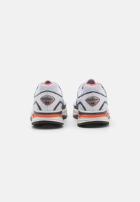 White and gray athletic shoes with mesh uppers, orange accents, padded collars, and black soles; features branding at the heel.