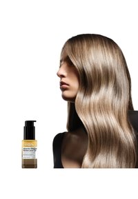 El aceite molecular Absolut Repair de L'Oréal en un frasco transparente con un dispensador negro, resaltando un cabello lacio, brillante y castaño claro.