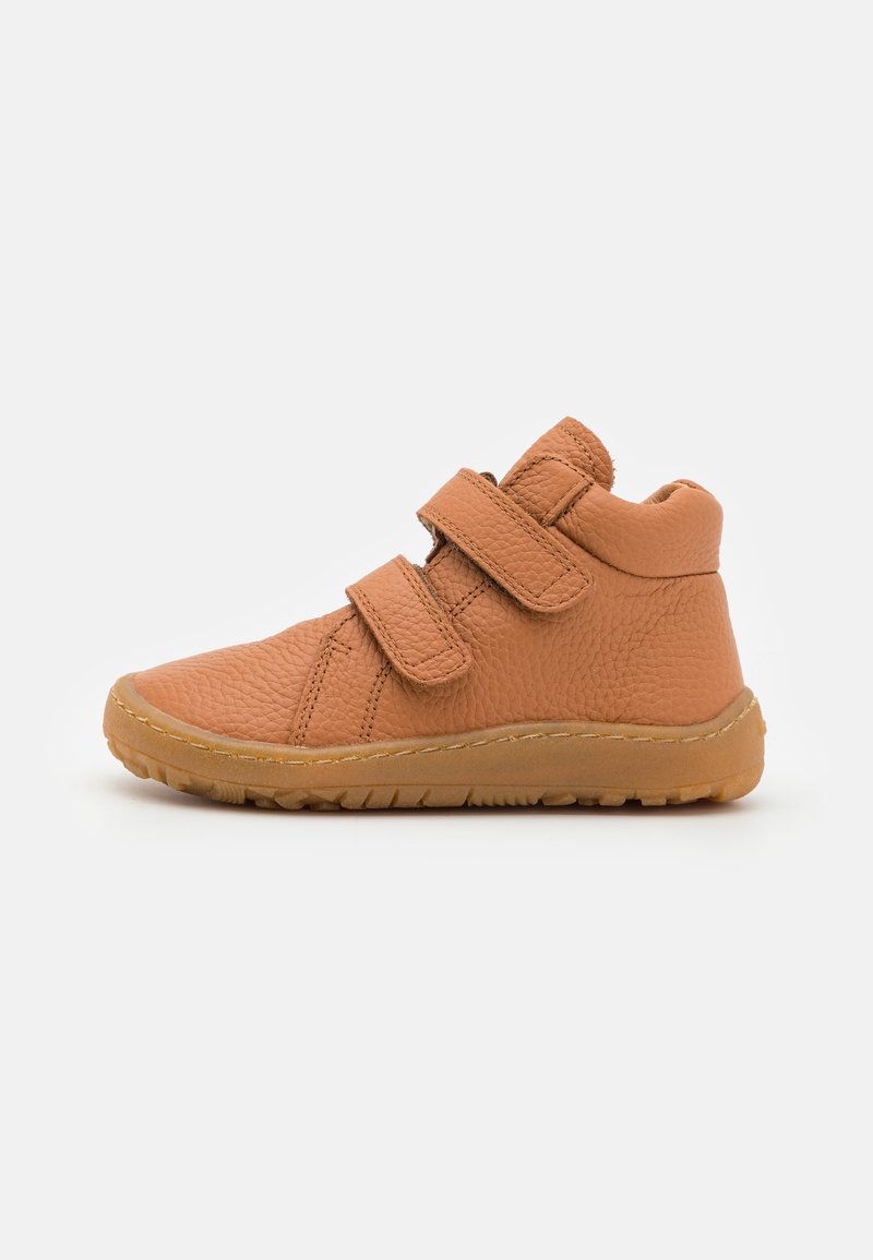 Chaussure enfant montante beige avec deux sangles réglables à scratch et semelle en caoutchouc texturée sur fond blanc.