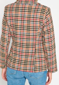 Marynarka w wzór houndstooth w odcieniach brązu, czerwieni i niebieskiego, z długimi rękawami i dopasowanym krojem. Materiał z teksturowanej mieszanki wełny.