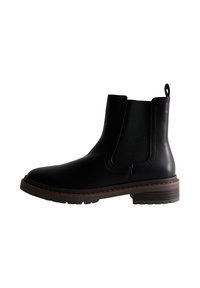 Botas de cuero negras hasta el tobillo con paneles elásticos en los lados, punta redonda y un tacón marrón apilado. Cuenta con una lengüeta para facilitar su uso.