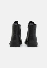 Stivaletti neri in pelle con finitura testurizzata, dotati di chiusura con zip e suola in gomma resistente. Il tacco misura circa 3 cm.