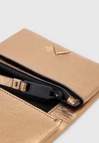 Pochette in pelle dorata con una finitura texturizzata, presenta una cerniera nera e un accento triangolare. Design compatto, adatta per oggetti piccoli.