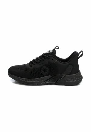 Zapatilla deportiva negra con parte superior de malla transpirable, acentos texturizados, suela acolchada con patrón de puntos y una lengüeta en el talón.