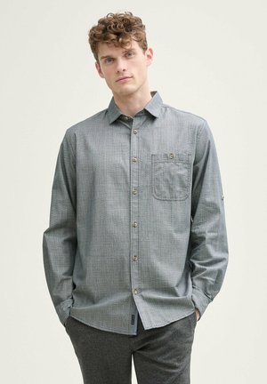 Lichte grijze button-up blouse van subtiele verticale strepen, met lange mouwen, een borstzak en een ronde zoom. De hardware heeft bruine knopen.