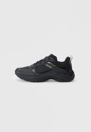Black athletic shoes featuring a textured upper, padded collar, reinforced toe, and thick sole with a logo accent on the side.