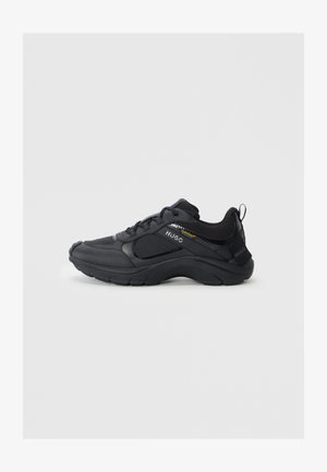 Black athletic shoes featuring a textured upper, padded collar, reinforced toe, and thick sole with a logo accent on the side.