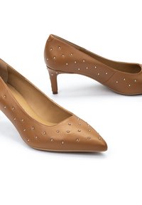 Escarpins en cuir marron avec un bout pointu et un talon de 5 cm. Présentent des rivets en argent décoratifs sur les côtés pour un détail supplémentaire.