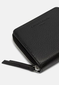 Schwarzes Lederportemonnaie mit strukturiertem Finish, ausgestattet mit einem silbernen Reißverschluss und einem Lederanhänger. Der Markenname ist auf der Vorderseite eingeprägt.