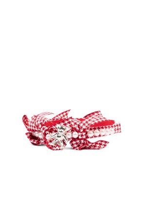 Pulsera de tela con estampado pata de gallo rojo y blanco, con cuentas de perlas y un pequeño colgante de oso de plata sobre un fondo blanco.