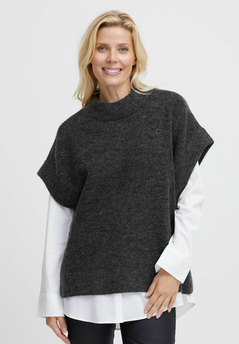 Dunkelgrauer, kurzärmliger Strickpullover mit hohem Kragen. Tragend über einem weißen Hemd mit Kragen, zeichnet sich durch eine lockere Form und eine weiche Textur aus.