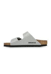 Silberne Glitzer-Sandale mit Korkfußbett und verstellbarem Riemen. Besitzt eine schwarze Sohle und Birkenstock-Logo an der Seite.