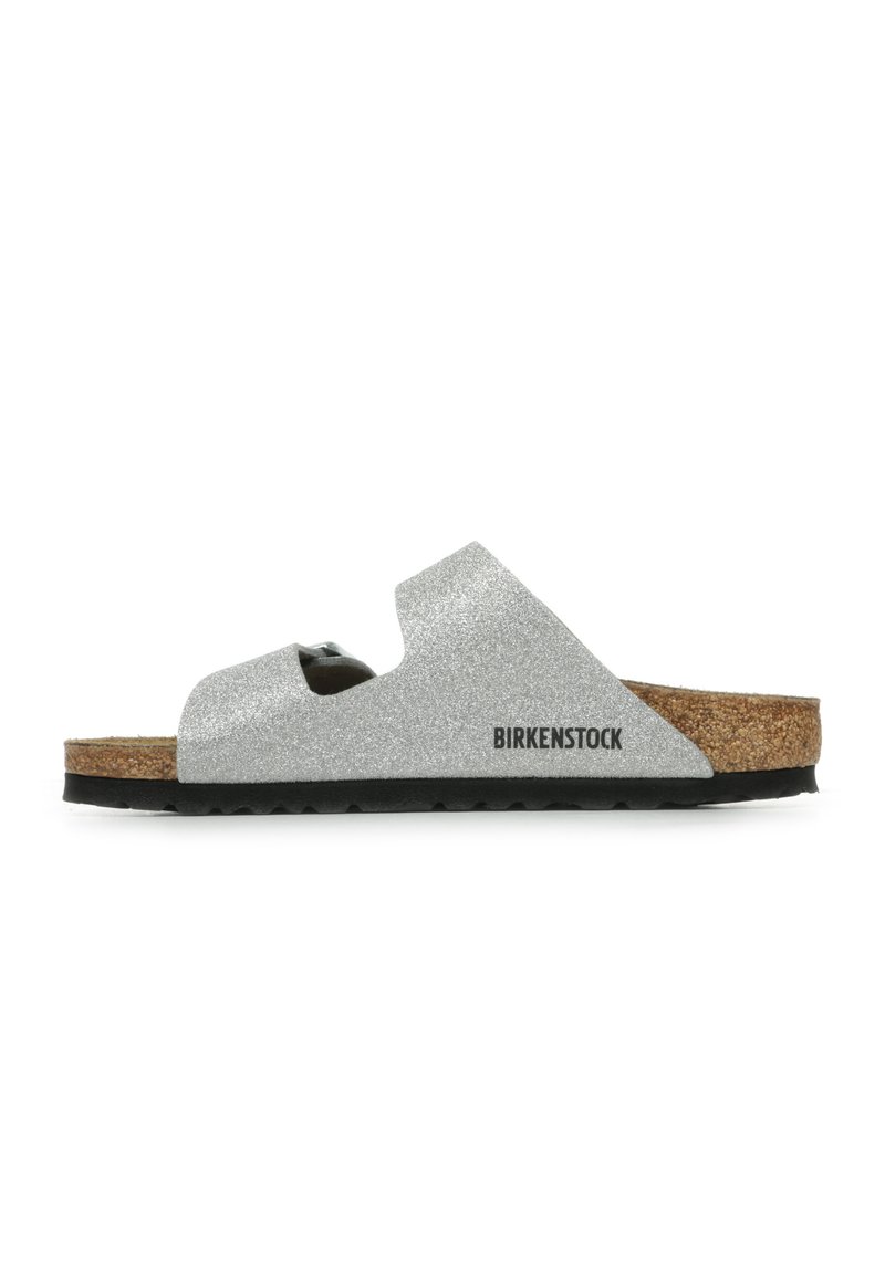 Silberne Glitzer-Sandale mit Korkfußbett und verstellbarem Riemen. Besitzt eine schwarze Sohle und Birkenstock-Logo an der Seite.
