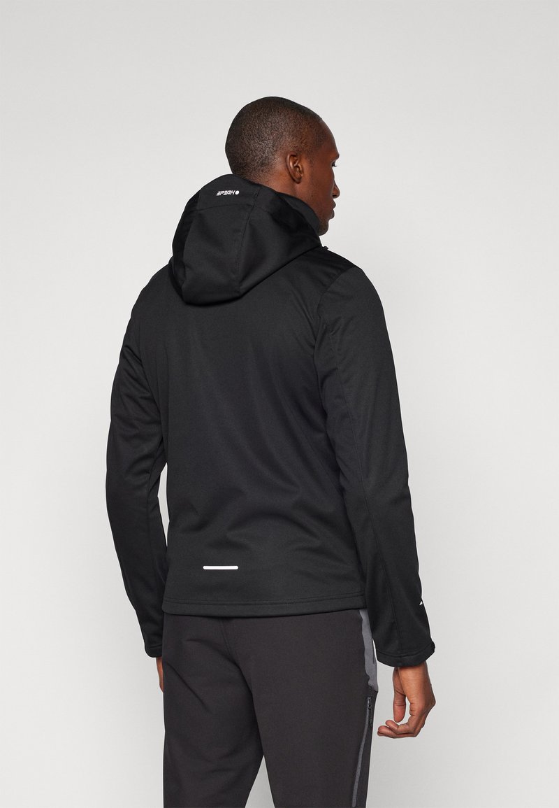 Schwarze Kapuzenjacke mit glatter Textur, die über reflektierende Akzente und ein tailliertes Design verfügt. Sichtbare Nähte und minimale Markenkennzeichnung.