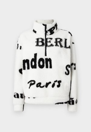 Pulover alb din fleece cu guler înalt, având text negru care include nume de orașe. Textură moale și închidere frontală cu fermoar pe jumătate.