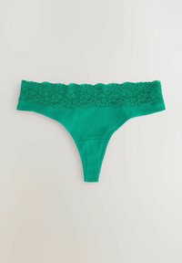 Tanga s zeleným krajkovým lemem a hladkým tělem. Pas je zdobený složitou květinovou krajkou. Oblékání je lehké a elastické.