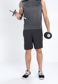 Conjunto deportivo que incluye una camiseta sin mangas de color gris oscuro, pantalones cortos negros y zapatillas negras. Pesas en las manos; diseño simple sin patrones.