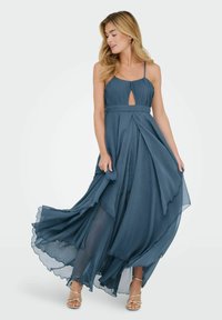 Sukienka maxi w kolorze teal, z falującymi plisami, detalem w kształcie dziurki w dekolcie, regulowanymi ramiączkami oraz warstwową spódnicą z chiffonu.