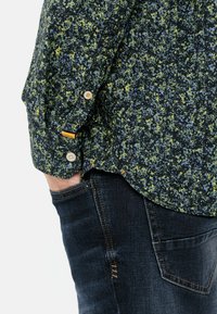 Hemd mit Blumenmuster in Dunkelblau, Grün und Gelb, aus einem Stoff mit strukturiertem Finish. Verfügt über zwei Knöpfe an den Manschetten und ein Etikett.